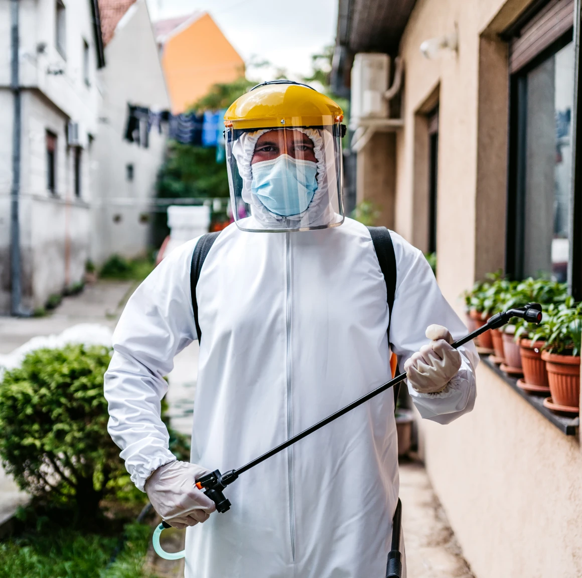 Person in protective gear spraying outdoors